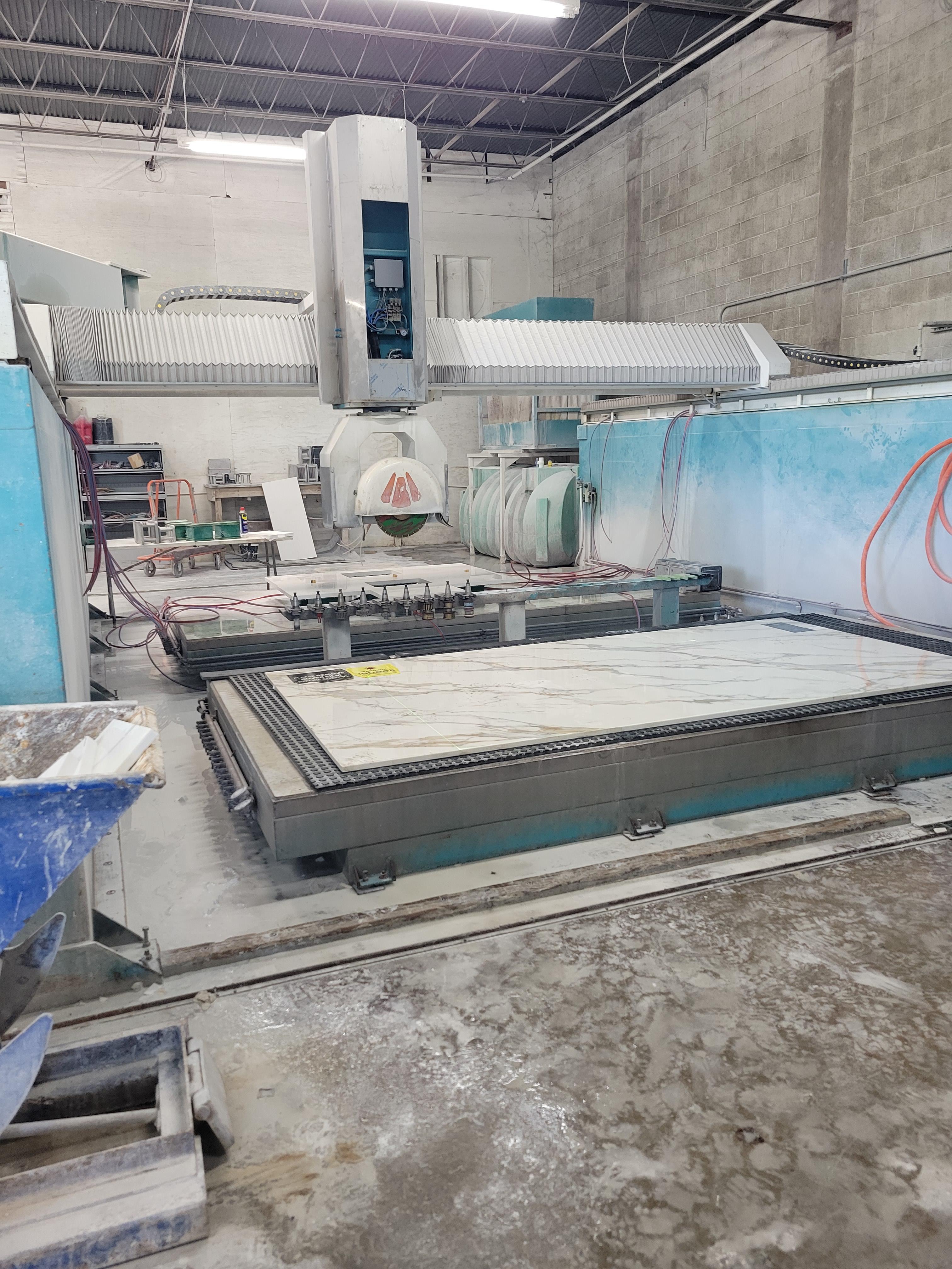 Teleo Countertops fabrication shop with a 5-axis CNC bridge saw cutting a marble slab